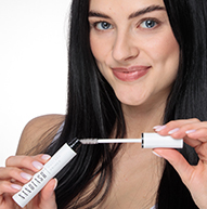 Een vrouw houdt elegant een tube Nanolash-mascara vast en laat haar schoonheid en zelfvertrouwen zien in een stijlvolle omgeving.