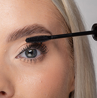 Een vrouw gebruikt een mascaraborstel om mascara aan te brengen, waardoor haar wimpers vakkundig worden geaccentueerd voor een dramatischer uiterlijk.
