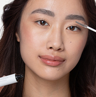 Een vrouw is gefocust op het aanbrengen van make-up met een penseel, waarbij haar kunstenaarschap en persoonlijke verzorgingsproces worden benadrukt.