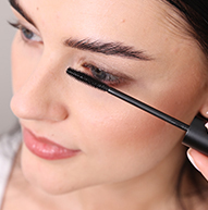 Een vrouw gebruikt vakkundig een mascaraborstel om mascara aan te brengen, waarbij ze zich concentreert op haar wimpers om een gedefinieerde look te bereiken.
