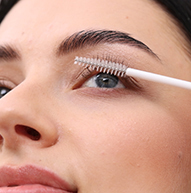 Een vrouw gebruikt een borstel om mascara aan te brengen, waarbij haar wimpers minutieus worden geaccentueerd om een gepolijste en verfijnde uitstraling te verkrijgen.